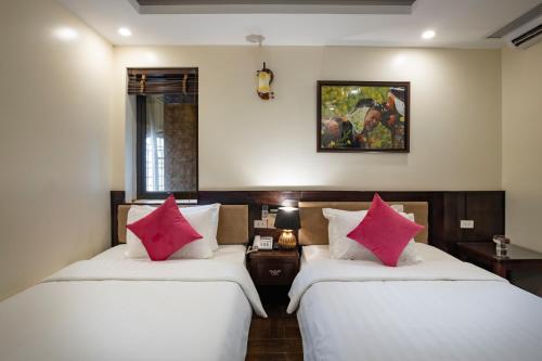 two beds in a room with two pink pillows at Sapphire Sapa Hotel in Sapa