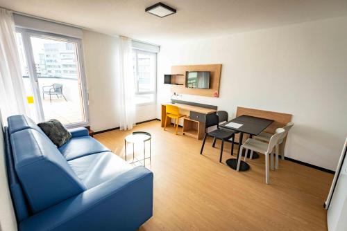 a living room with a blue couch and a table at Apparthotel Le Hüb Grenoble in Grenoble