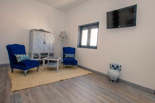 a living room with two blue chairs and a tv at Casa do Leão in Marialva