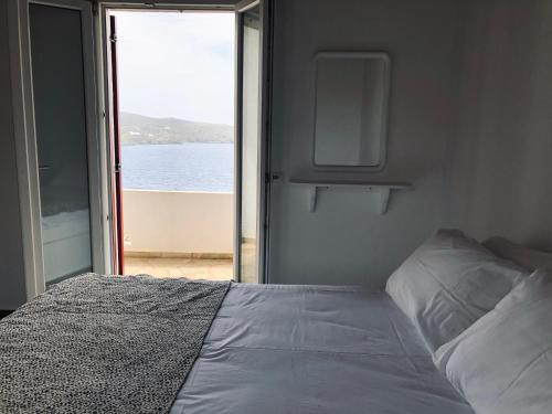 a bedroom with a bed with a view of the water at En Plo in Agios Romanos