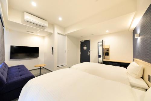um quarto com uma cama branca e um sofá azul em Hotel NewNagano NeXT em Nagano