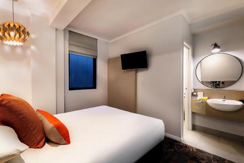 a hotel room with a white bed and a sink at Batman's Hill on Collins in Melbourne