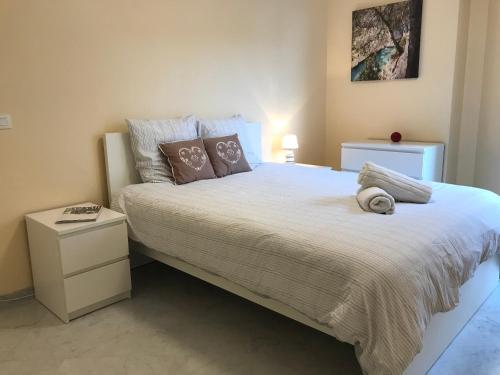 une chambre avec un grand lit blanc avec des oreillers dans l'établissement Le Victoria, 2p moderne, les pieds dans l'eau, Parking, Piscine, à Menton