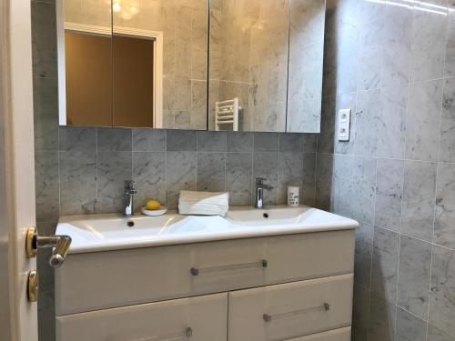 La salle de bains est pourvue d'un lavabo blanc et d'un miroir. dans l'établissement Le Victoria, 2p moderne, les pieds dans l'eau, Parking, Piscine, à Menton