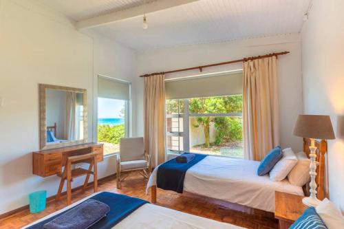 1 dormitorio con cama, escritorio y ventana en Anna's On The Beach, en Cape St. Francis