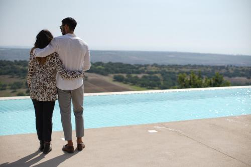a man and a woman standing next to a pool at Relais Chiaramonte in Ragusa