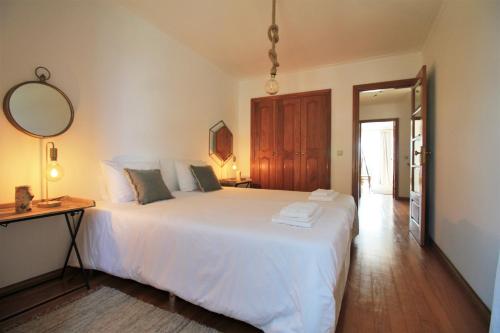 1 dormitorio con 1 cama blanca grande y espejo en Ocean House - First Line of Cabedelo Beach, en Viana do Castelo