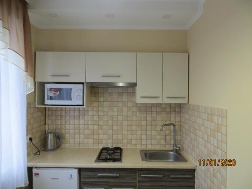 a kitchen with white cabinets and a sink at Замечательная квартира с современным ремонтом рядом с метpо Холодная гора in Kharkiv