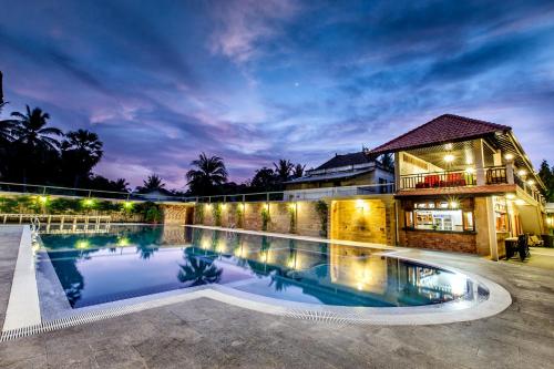 a swimming pool in front of a building at night at Classy Hotel in Battambang