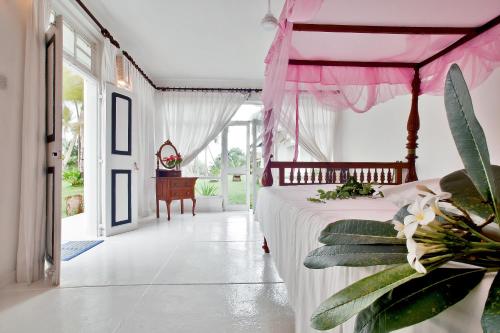 a bedroom with a bed with a pink canopy at Chitra Ayurveda in Bentota