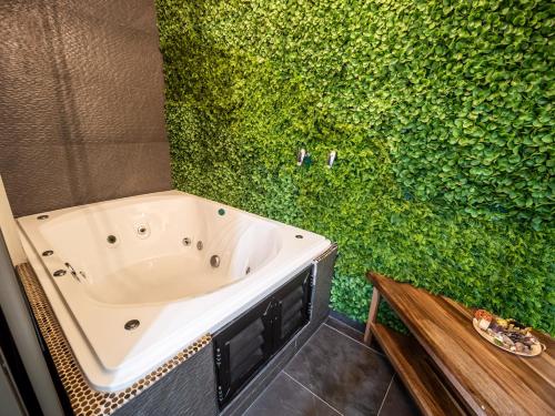 a bathroom with a green wall with a bath tub at Hotel DC Boutique & SPA in Puerto Escondido