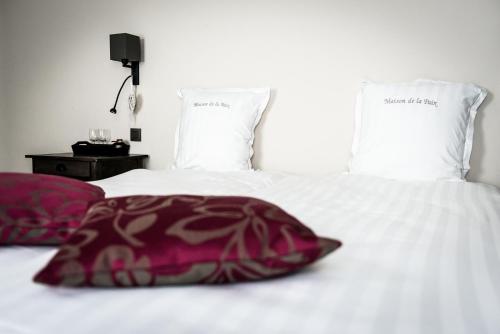 a bed with a red pillow and two white pillows at Maison de la Paix in Poperinge