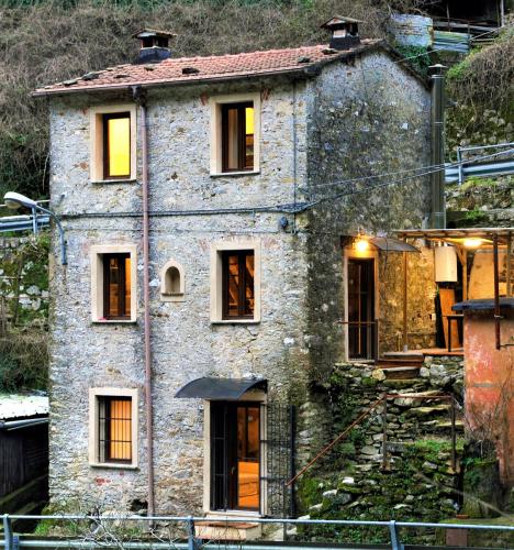 an old stone house with windows on a hill at Incantevole casa sul fiume, Relax e Natura ai piedi della Alpi Apuane in Massa