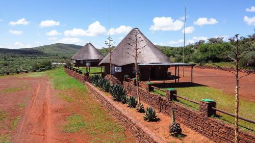two huts with thatched roofs next to a dirt road at Red Sands Country Lodge in Kuruman