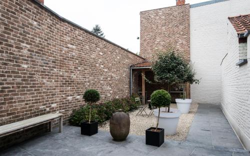 une cour avec des plantes en pot et un bâtiment en briques dans l'établissement Maison de la Paix, à Poperinge