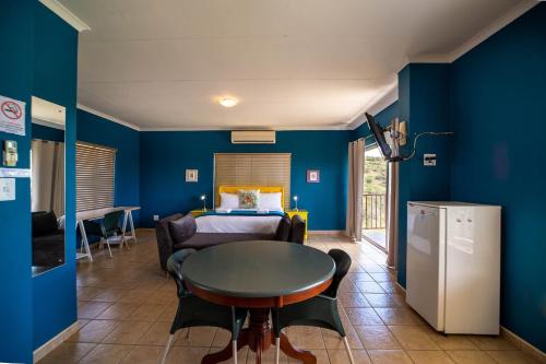 a room with blue walls and a table and a bed at Red Sands Country Lodge in Kuruman