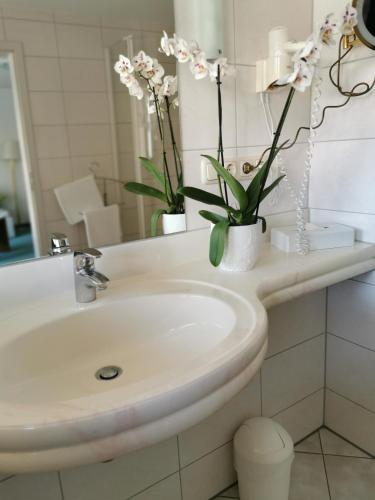 a bathroom with a sink and flowers in a mirror at Hotel Cristal in Nürnberg
