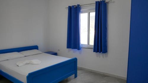 a bedroom with a blue bed and a window at Doci Seven Hotel in Velipojë
