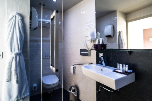 a bathroom with a sink and a toilet and a shower at Hotel de la Paix in Poperinge
