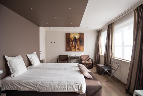 een slaapkamer met een groot bed en een stoel bij Hotel de la Paix in Poperinge