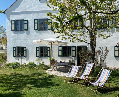 two chairs and an umbrella in front of a house at Benefizium Denklingen - Anno 1713 in Denklingen