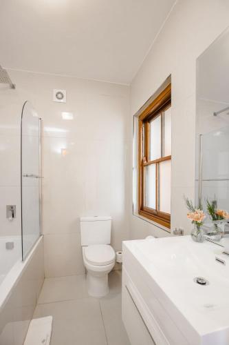 a white bathroom with a toilet and a sink at Roosenwijn Guesthouse in Stellenbosch