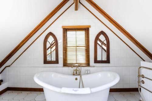 a bath tub in a bathroom with a roof at Roosenwijn Guesthouse in Stellenbosch