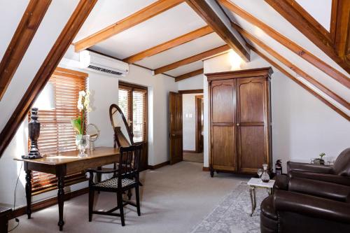 a living room with a table and a wooden cabinet at Roosenwijn Guesthouse in Stellenbosch