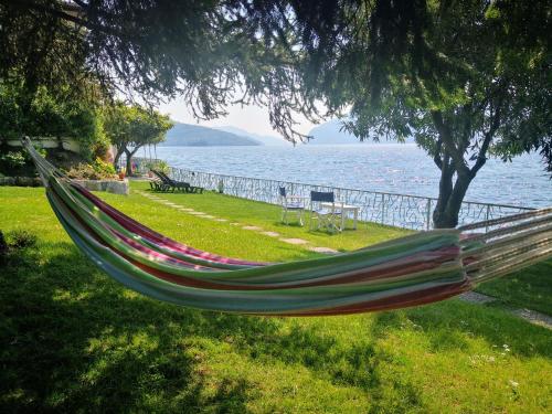 a hammock hanging from a tree next to the water at La Casina a Remi in Marone