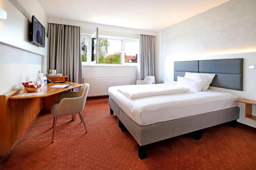 ノイ・イーゼンブルクにあるチューリップ イン フランクフルト エアポートの大きなベッドとデスクが備わるホテルルームです。
