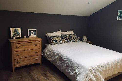 a bedroom with a white bed and a wooden dresser at Numéro 9 in Légna