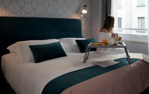 
a bed with a white comforter and pillows on it at Duomo Hotel & Apartments in Milan
