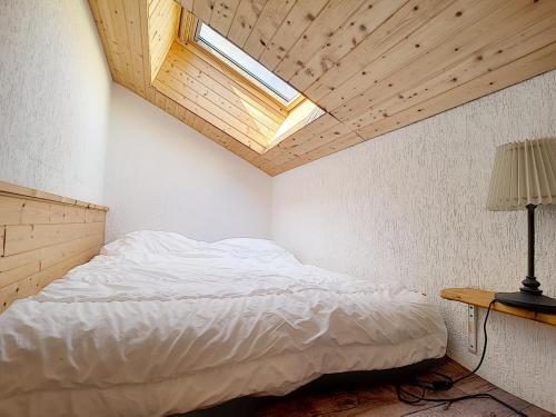 1 dormitorio con 1 cama blanca y tragaluz en LOCATION APPARTEMENT SPACIEUX AVEC BALCON - SAINT JEAN D'AULPS STATION - 6 Personnes - RELAIS D15, en Saint-Jean-dʼAulps