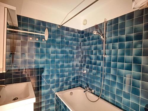 La salle de bains est pourvue de carrelage bleu, d'une baignoire et d'une douche. dans l'établissement LOCATION APPARTEMENT SPACIEUX AVEC BALCON - SAINT JEAN D'AULPS STATION - 6 Personnes - RELAIS D15, à Saint-Jean-dʼAulps