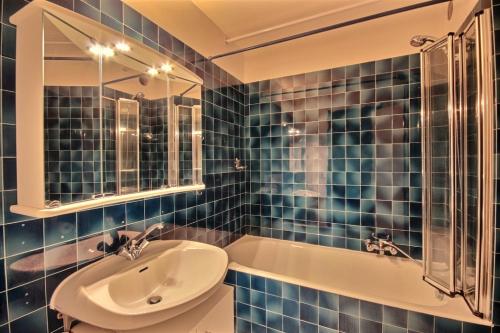 baño de azulejos azules con lavabo y bañera en LOCATION APPARTEMENT CENTRE STATION SAINT JEAN D'AULPS STATION - 6 Personnes - RELAIS S1, en Saint-Jean-dʼAulps