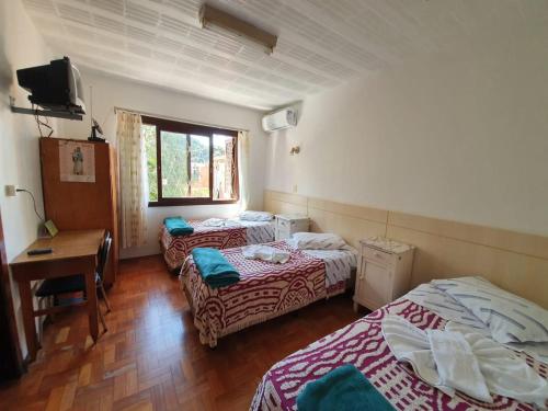een kamer met 2 bedden, een bureau en een raam bij Casa Santa Cruz in Passo Fundo