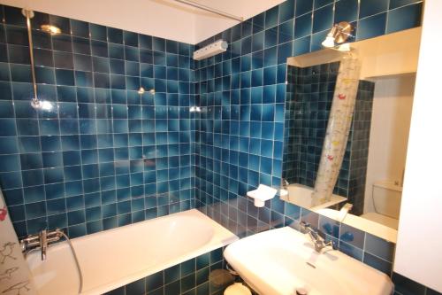 uma casa de banho em azulejos azuis com uma banheira e um lavatório em APPARTEMENT PIED DES PISTES - SAINT JEAN D'AULPS STATION - 4 Personnes - RELAIS S36 em Saint-Jean-dʼAulps