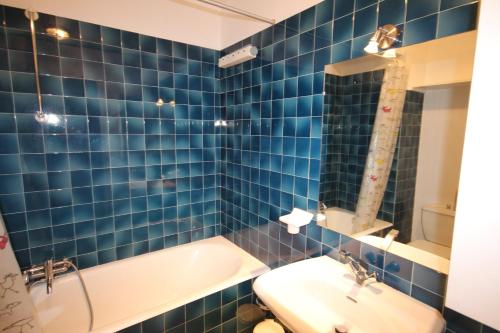La salle de bains est pourvue de carrelage bleu, d'une baignoire et d'un lavabo. dans l'établissement APPARTEMENT PIED DES PISTES - SAINT JEAN D'AULPS STATION - 4 Personnes - RELAIS S36, à Saint-Jean-dʼAulps