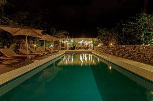 a swimming pool at night with chairs and umbrellas at Na’ankusê @ Utopia in Windhoek