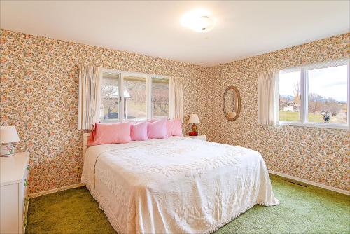 a bedroom with a large bed with pink pillows at Linger Longer Lakeside Cottage in Oroville