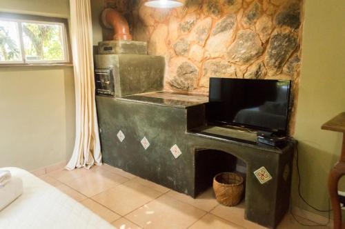 a stove in a kitchen with a stone wall at Pousada Papyrus in Tiradentes
