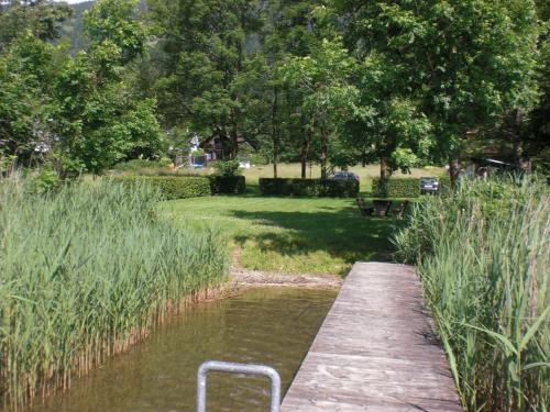 a wooden bridge over a river with tall grass at Ferienwohnung Landhaus Sorli in Bodensdorf