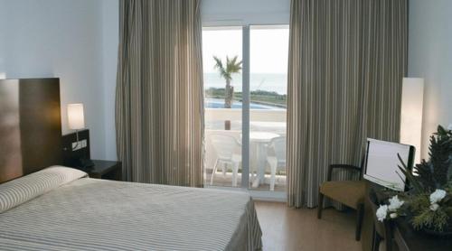 a hotel room with a bed and a desk with a computer at Garbí Costa Luz in Conil de la Frontera