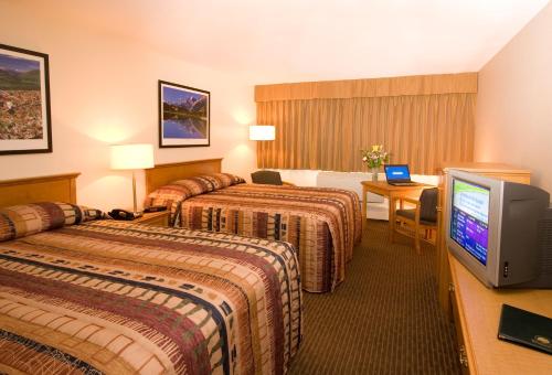 a hotel room with two beds and a television at Woodlands Inn & Suites in Fort Nelson