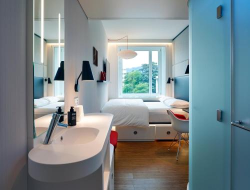 a bedroom with a bed and a sink and a mirror at citizenM Zürich in Zürich