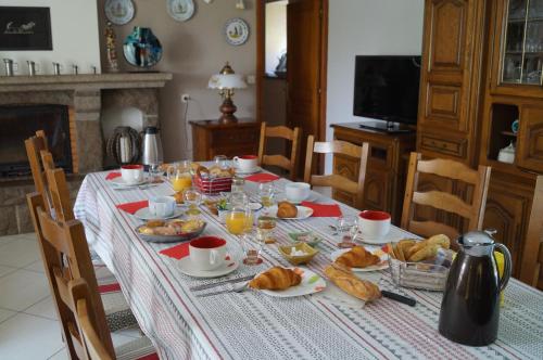 einen Tisch mit einem Frühstück mit Croissants und Orangensaft in der Unterkunft Chambres d'Hôtes La Loubatais in Dol-de-Bretagne