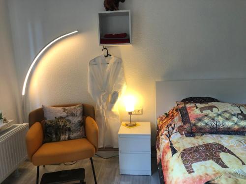um quarto com uma cama e uma cadeira ao lado de um candeeiro em Maggies-Apartment-Hannover em Hanôver