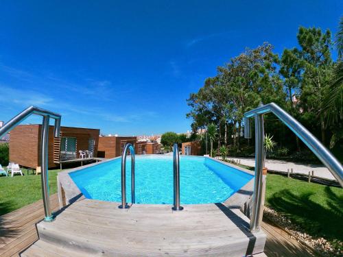 une piscine avec une promenade en bois menant à une piscine dans l'établissement Golden Halcyon - Ericeira Villas, à Ericeira