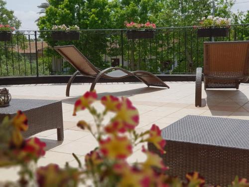 a patio with chairs and tables and a fence with flowers at Hotel Le Torri in Arborea 