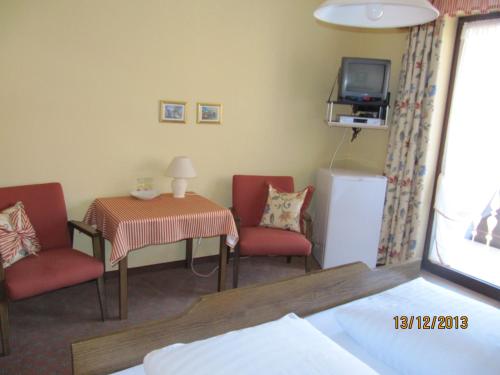 a room with two chairs and a table and a tv at Gasthaus-Krone-Post in Simonswald